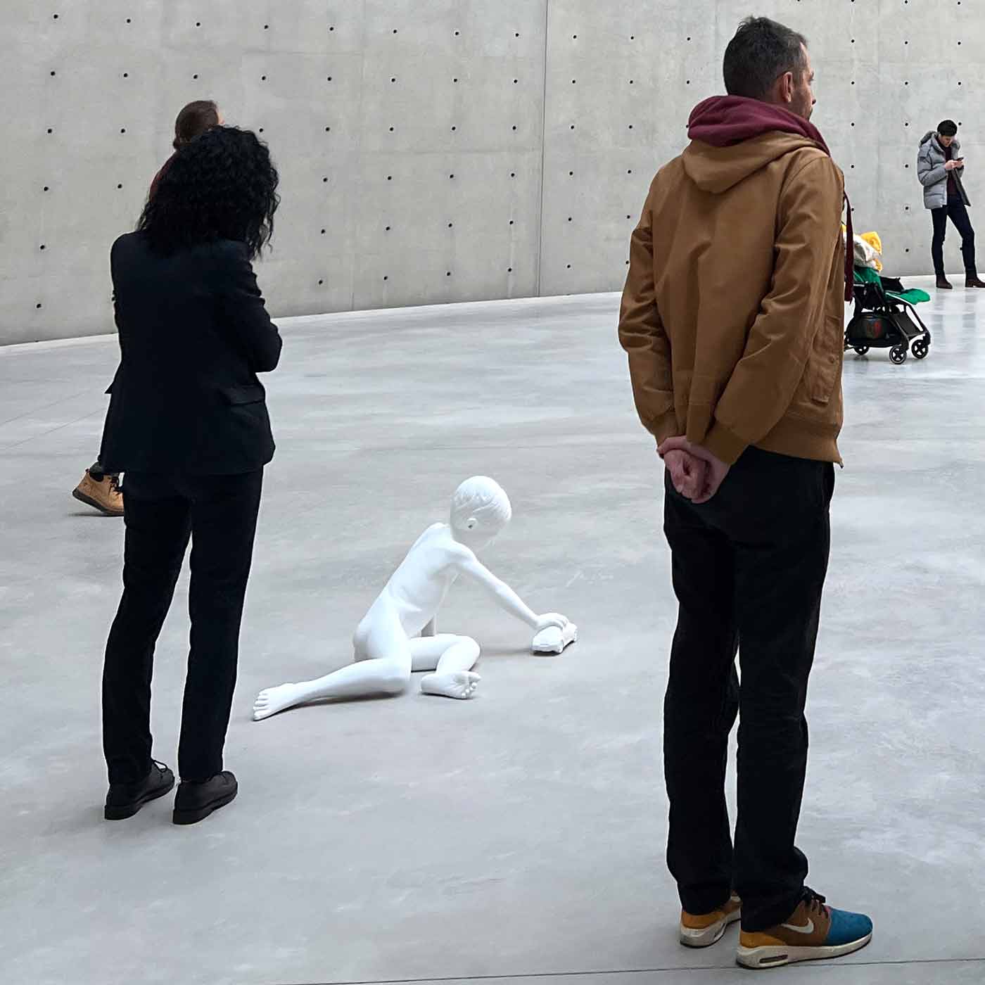 weiße Skulptur eines kleinen Jungens, in mitten von Museums-Besuchern