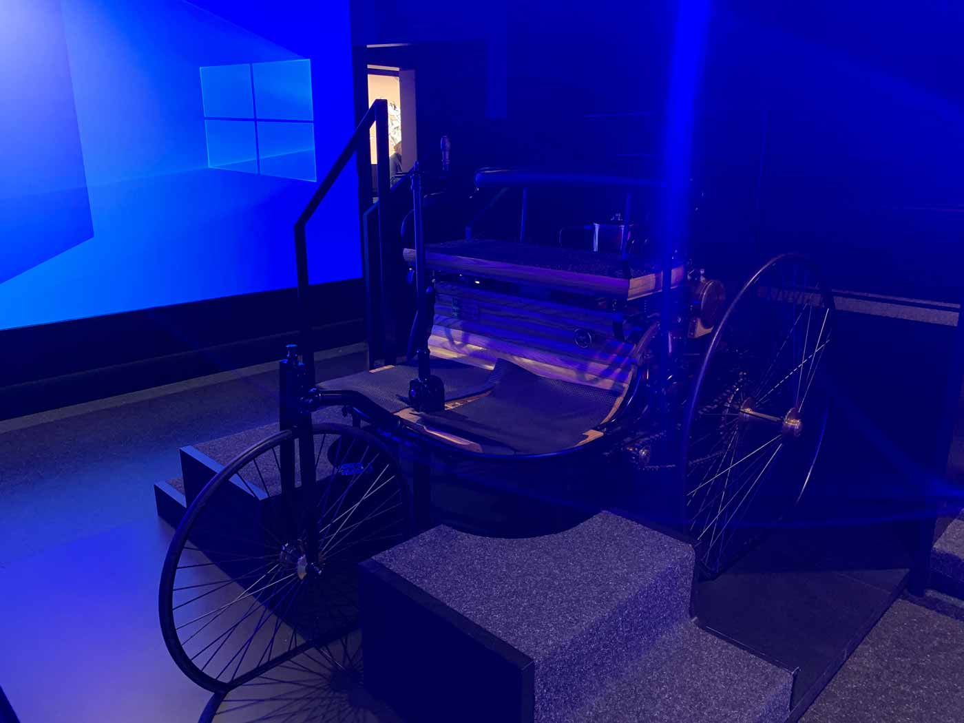 Ausstellungsraum mit blauer Projektionswand und Modell eines Automobils